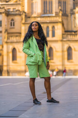 Fototapeta premium Lifestyle of a young girl of black African ethnicity with a beautiful green suit. Sightseeing in the city
