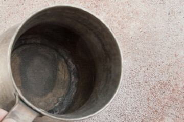 Antique metal cup on a concrete background.