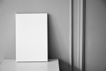 White canvas mockup, blank picture on wooden table in interior with grey wall