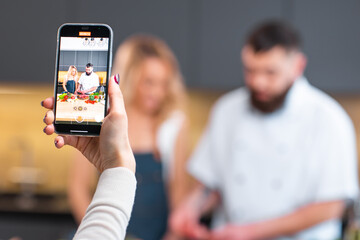 Young woman and man prepare food and host a cooking show. The bloggers stream from modern kitchen. Healthy food preparation.