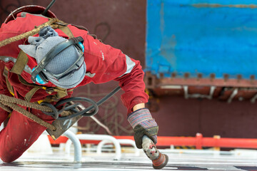 Seaman ship crew working aloft at height derusting and getting vessel ready for painting.