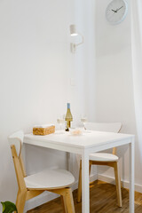 A white table with wine, perfect for a couple in a bright minimalist room.
