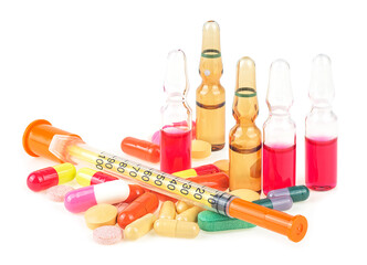 Syringe with glass vials and medicinal tablets and pills isolated on a white background. Assorted...
