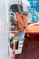 Seaman ship crew working aloft at height painting ships superstructure.