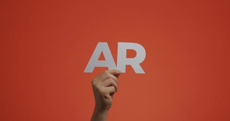 Hand raising up showing augmented reality sign. 4k video of arm with letters ar made of carved paper