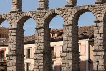Obraz premium Detail of the granite arches of the Aqueduct of Segovia, crossed by swallows birds, next to the Plaza del Azoguejo