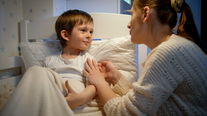 Little sick boy coughing in bed and talking to his loving mother. Concept of child virus and kids...