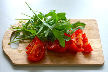 Geschnittene Tomate und Rucola auf einem Holztablett, Kochen, Essen, Gesundheit, mediterrane Küche 