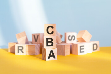 wooden cubes with letters CBA arranged in a vertical pyramid, yellow background