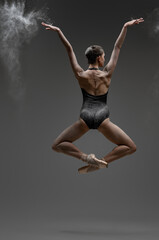 Backview shot of jumping ballerina with outstretched arms