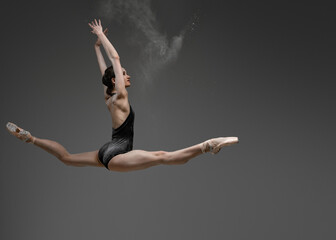 Fototapeta premium Leaping woman with raised arms against gray background