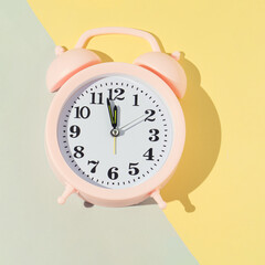 The alarm clock in pink on a yellow and gray background displays 5 minutes to 12