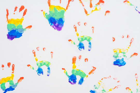 Child handprints of rainbow colors, on white sheet of paper. Top view