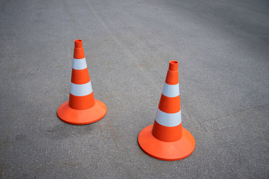 Two Orange Construction Cones With Reflective Stripes On An Asphalt Road, Repair Of The Roadbed On The Motorway