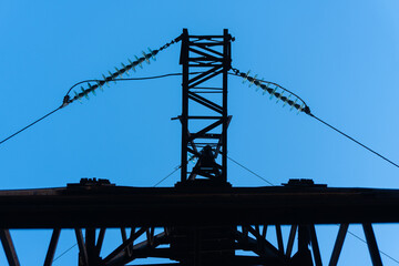A close-up view of a rusted steel power transmission tower in Ukraine, featuring high-voltage lines and insulators. This aging infrastructure reflects the ongoing use of Soviet-era energy systems unde