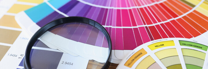 Color swatches and magnifying glass lying on table closeup