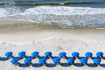 A drone shot of a beach resort set up with blue chairs and umbrellas