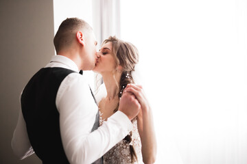 Beautiful bride and groom embracing and kissing on their wedding day