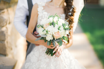 Beautiful young wedding couple posing with bouquet of flowers in hands
