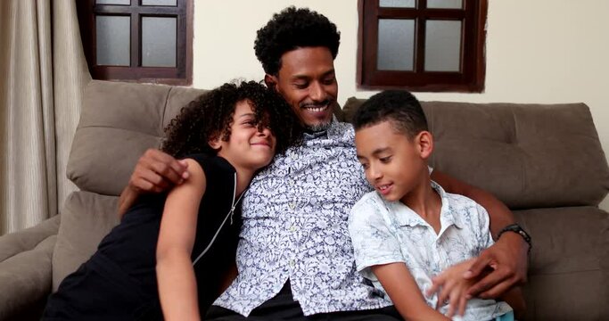 African father embracing daughter and son together at couch living-room