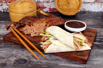 Aromatic half crispy duck with Chinese style pancakes, spring onions and hoisin sauce on a wooden...