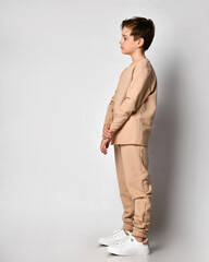 Serious thoughtful confident preteen boy child in fashion sportswear thinking looking forward on copy space standing . sideway over studio wall background. Children emotion and expression concept