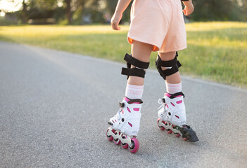 Fototapeta na wymiar The legs of a little girl as she is rollerblading on a sunny day.