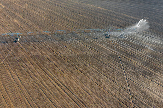 Aerial view about center pivot irrigation system spraying crops. Farm concept, modern watering equipment, agriculture texture.