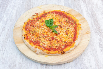 Typical recipe for simple margarita pizza with mozzarella cheese and tomato and basil leaves on wooden board