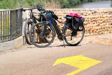 Fototapeta premium Way of St James , Camino de Santiago , yellow arrow sign on road and bicycles of pilgrims to Compostela , Galicia, Spain