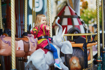 Fototapeta na wymiar Toddler having fun on vintage French merry-go-round in Paris, France