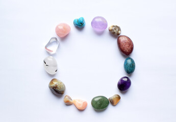 The circle is lined with natural minerals. Semi-precious stones of different colors, raw and processed. Amethyst, rose quartz, agate, apatite, aventurine on a white background.