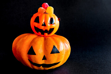 Happy Halloween decoration on black background. Pumpkin with colored gummy candies.