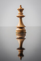the queen chess piece on white background with reflection in table
