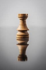rook chess piece on white background with table reflection.