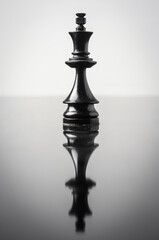 the king chess piece on white background with reflection in table