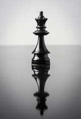 the queen chess piece on white background with reflection in table