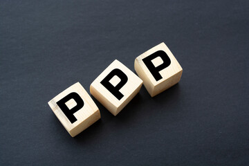 Word Public-Private Partnership PPP. Wooden small cubes with letters isolated on black background with copy space available. Business Concept image.