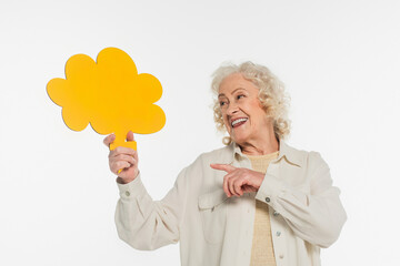 smiling elderly woman pointing with finger at yellow thought bubble in hand isolated on white
