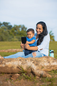 Latina Mom Taking Picture With Her Baby In The Green Field