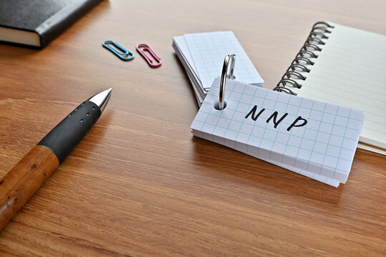 There is a card with the word of NNP which is an abbreviation for net national product on the desk with paper clips, a pen and notebook.