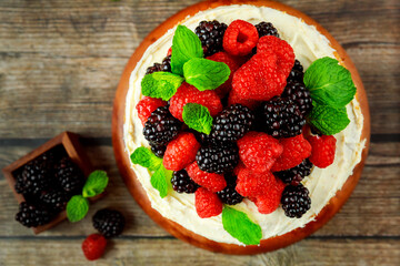 Top view of tasty berry cake decorated with fresh raspberries and blackberries.