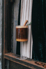 Orange and coffee cocktail topping with sliced orange on wooden background. Colorful cocktail drink in a relaxing afternoon at home.