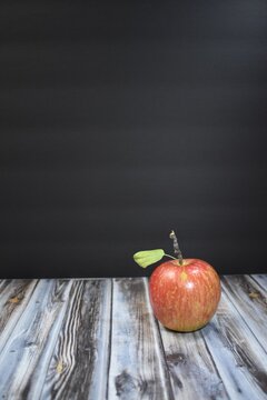 Red apple with a black background and wood table