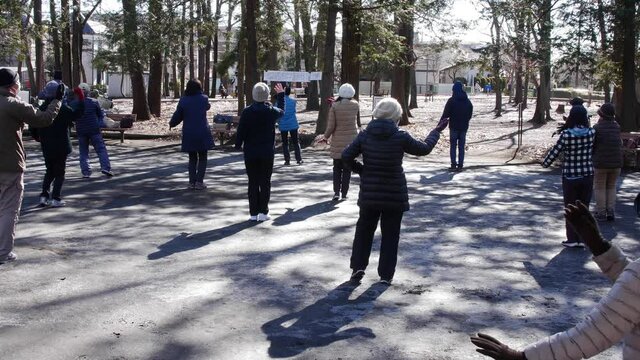 Asian elderly people practicing Tai Chi at a public park in Tokyo, Japan.