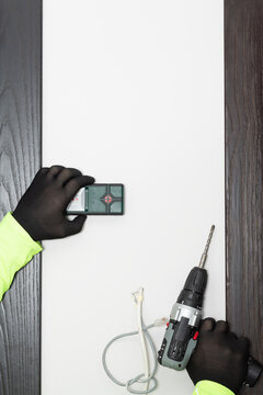 Stud Finder (metal And Cable Detector) And Drill In Hands Of Handyman On The Wall Background.