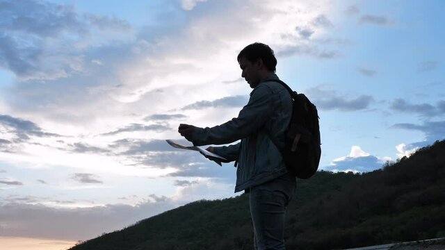 Young caucasian man traveler looking map and compass looking for a destination Slow motion shot. Male with backpacks on the mountain. Travel, Hiking, and adventure 