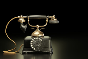Vintage brass and black iron telephone in dark background. It was a communication antique tool in the past that used a dial to call each other. Copy space for text. 3D illustration rendering.