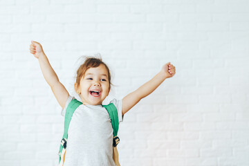 Happy child with raised hands up in front of white background