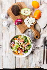 Vertical shot Mediterranean summer salad. Mussels, shrimp, salmon, tomatoes, ice salad, avocado, onion, Swiss chard and olive oil. Still life of seafood on a rustic background. Copy space. Top view